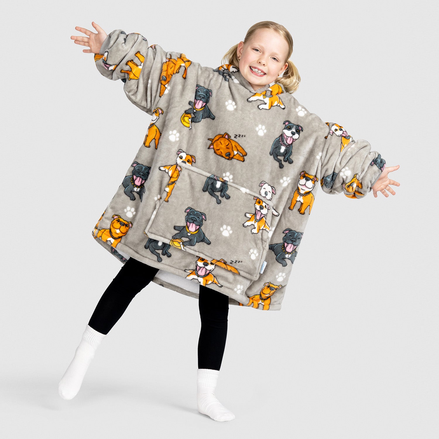 Child wearing a grey wearable blanket with cartoon Staffordshire Bull Terrier dog prints, smiling and posing with arms outstretched.