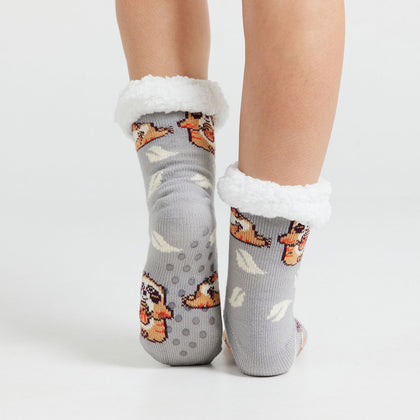 Pair of gray socks with white fluffy cuffs featuring a pattern of cartoon sloths and white leaves, worn on feet.