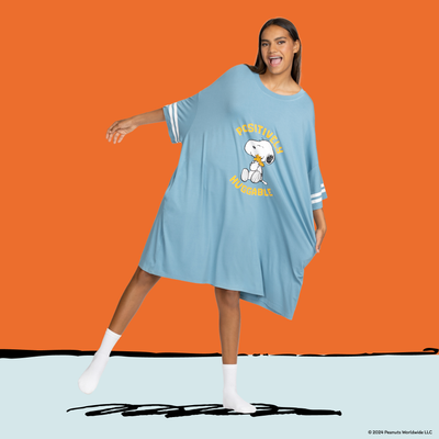 Woman wearing a loose blue dress with white stripes on the sleeves, featuring Snoopy hugging Woodstock and the text 