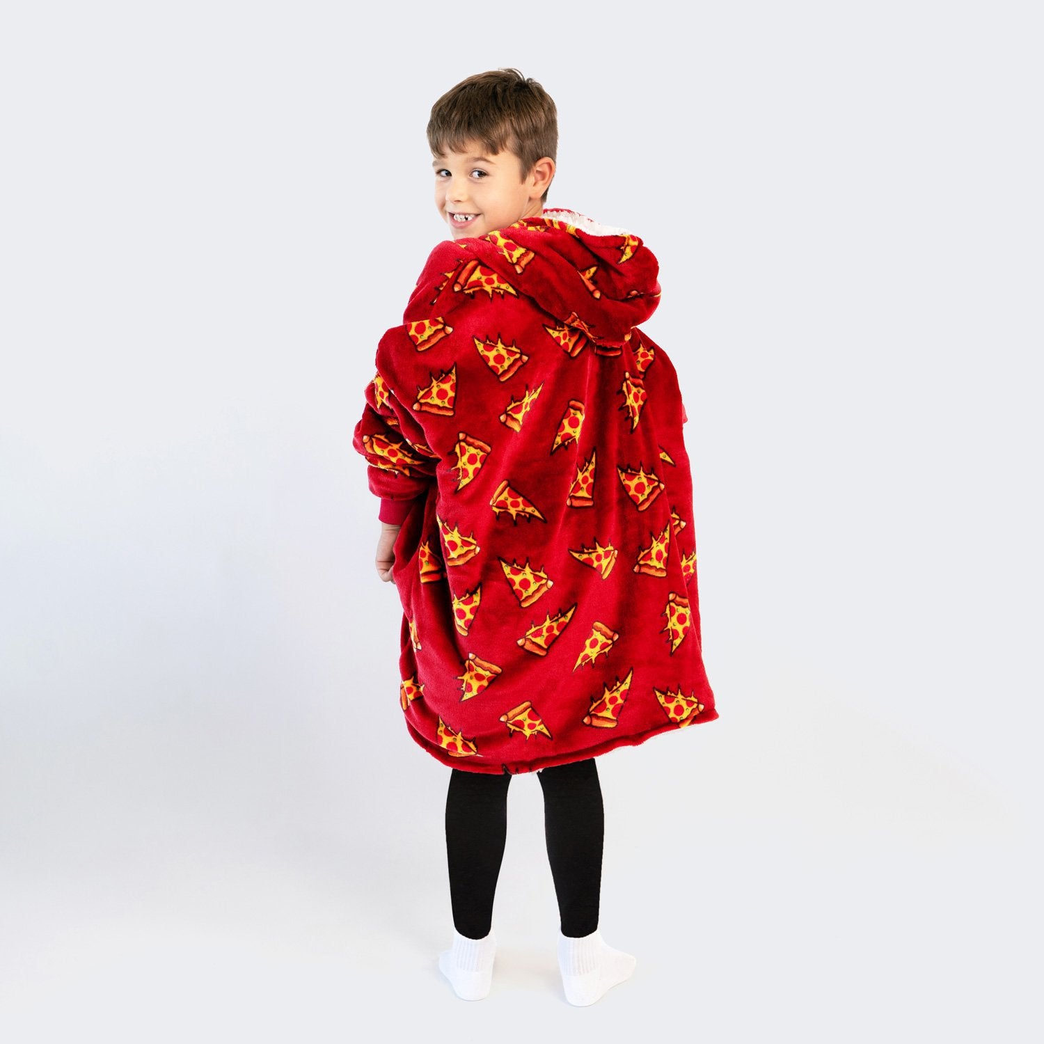 Child wearing a red hooded blanket with pizza slice patterns, looking over their shoulder.